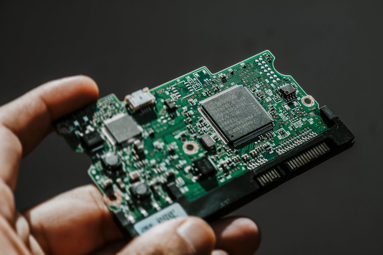 Close-up view of a green circuit board held by a hand, showcasing technology details.