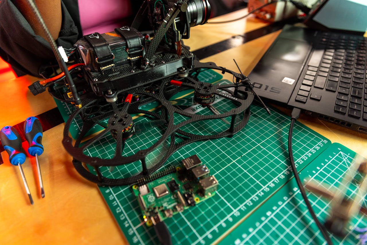 Drone assembly on a desk with laptop and tools, capturing modern tech.